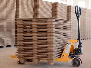 In the warehouse of molded pallets, there are a large number of pallets placed there, and one stack of molded pallets is piled on a small forklift truck.